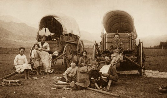 Weary travellers rest beside their wagon.