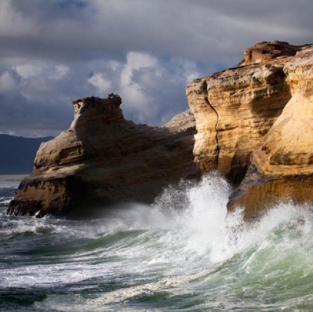 Waves crash against the cliffs.