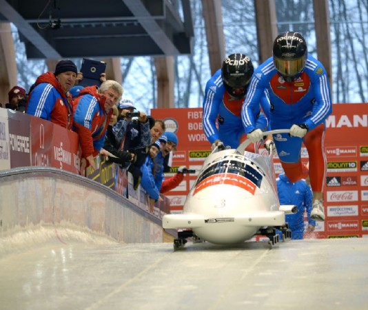 A two-man bobsleigh team begins a run.
