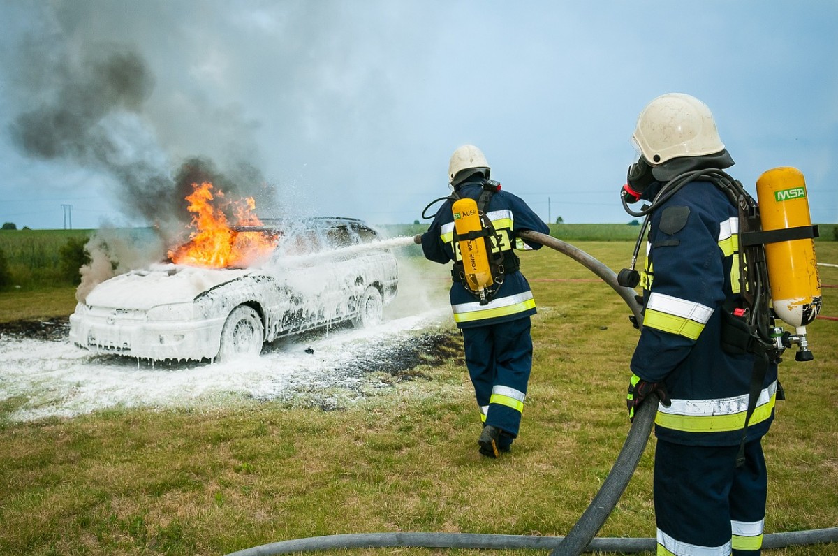 Firefighters spray foam on a car fire