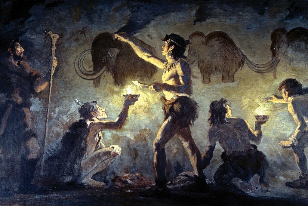 Artists painting woolly mammoths on a cave wall