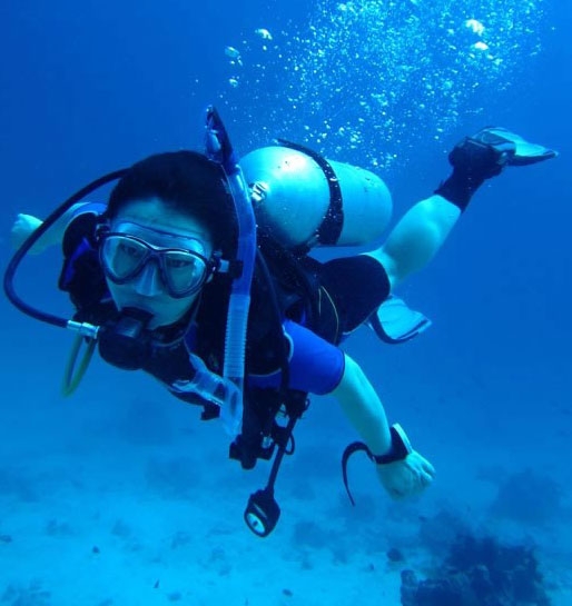 A scuba diver breathes oxygen from a tank on her back.