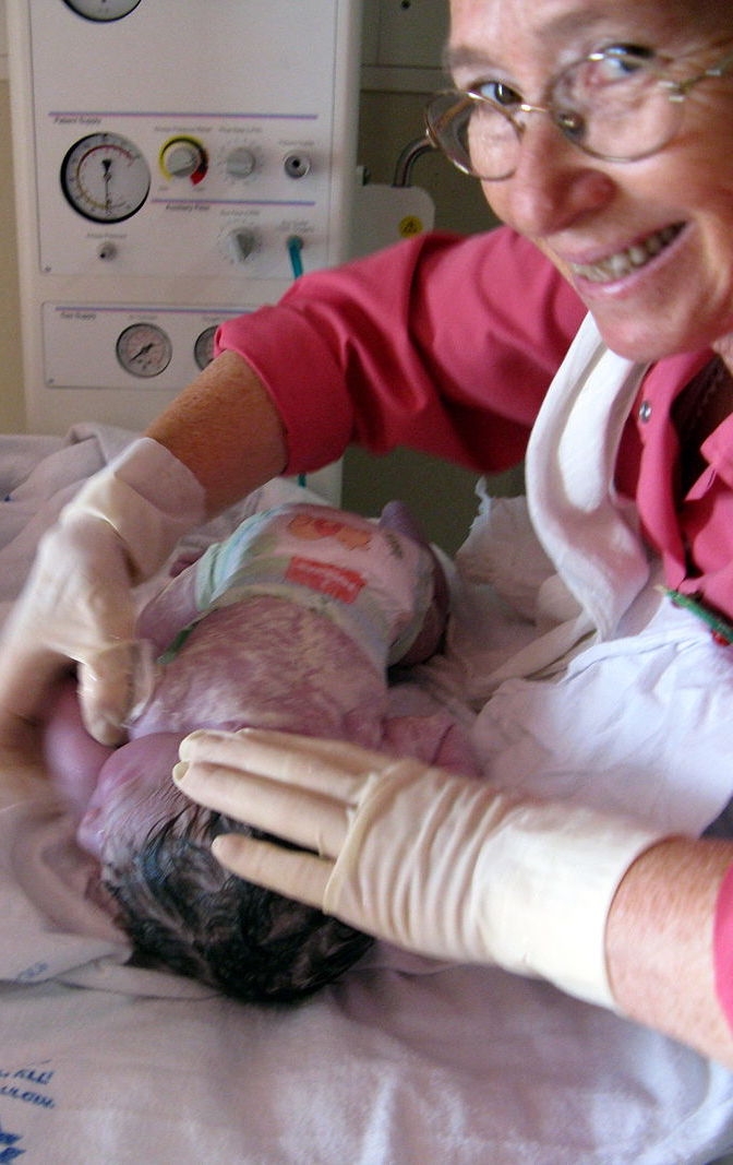 A baby girl with a midwife in the delivery room