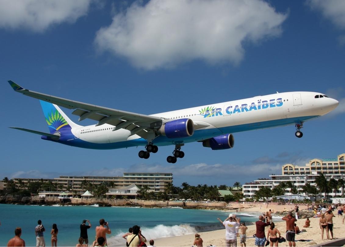 A plane flies low over the beach in Sint Maarten