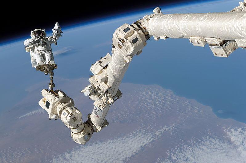 An astronaut anchored to a foot restraint on the robotic arm Canadarm2