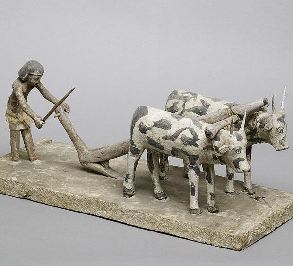 Model of a man using a simple wooden plough
