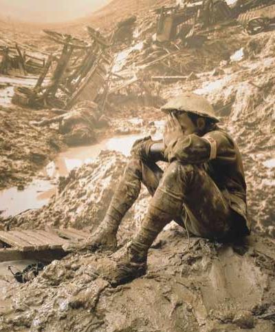 A soldier sits surrounded by mud and devastation