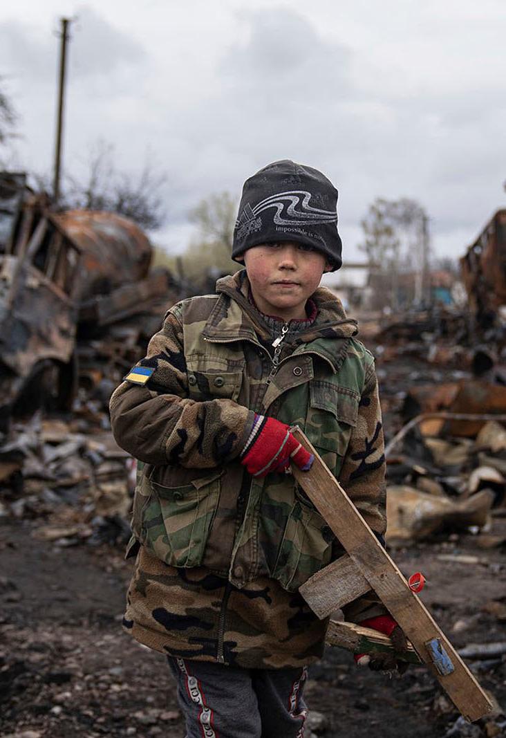 A boy stands by destroyed Russian military vehicles