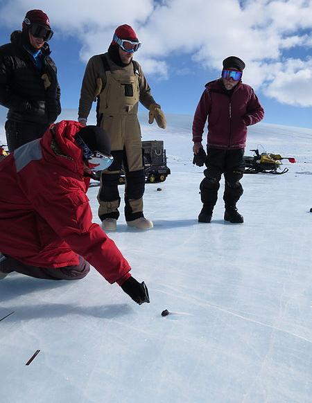 Researchers examine a meteorite on the ice in Antarctica