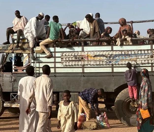 People board a truck to flee the fighting, October 2025