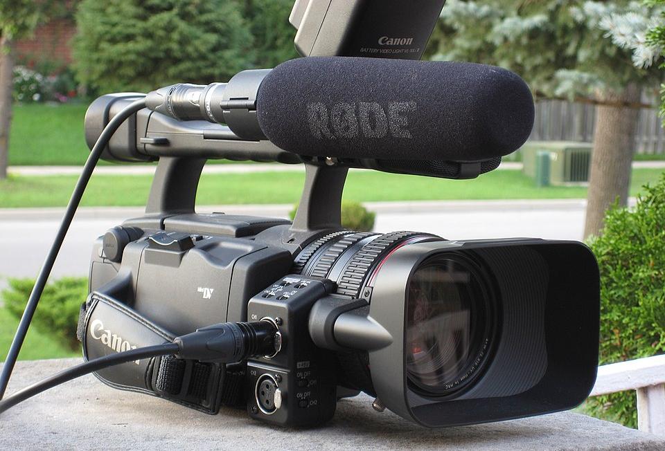 Camera fitted with a shotgun microphone covered by a foam windscreen