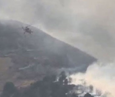 A helicopter battles a wildfire on a mountainside