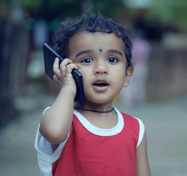 A boy speaks into a phone
