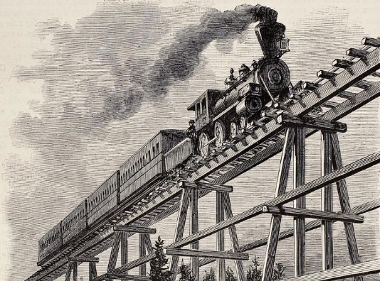 A train crosses a wooden trestle bridge