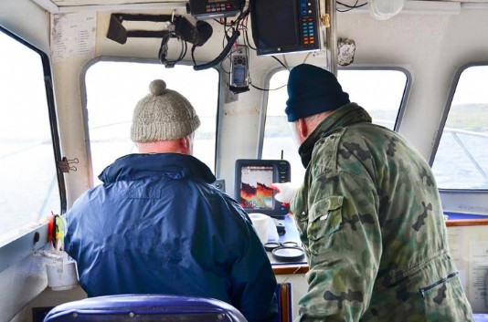 Fishermen study a sonar screen