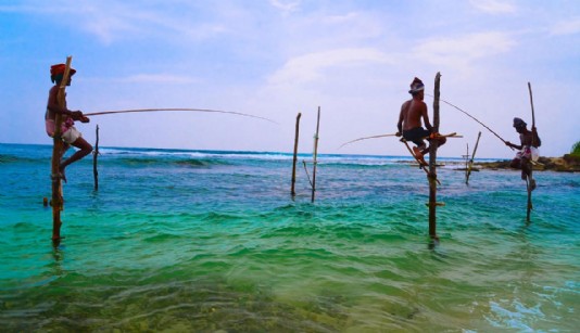 Fishermen in Sri Lanka squat on a timber pole